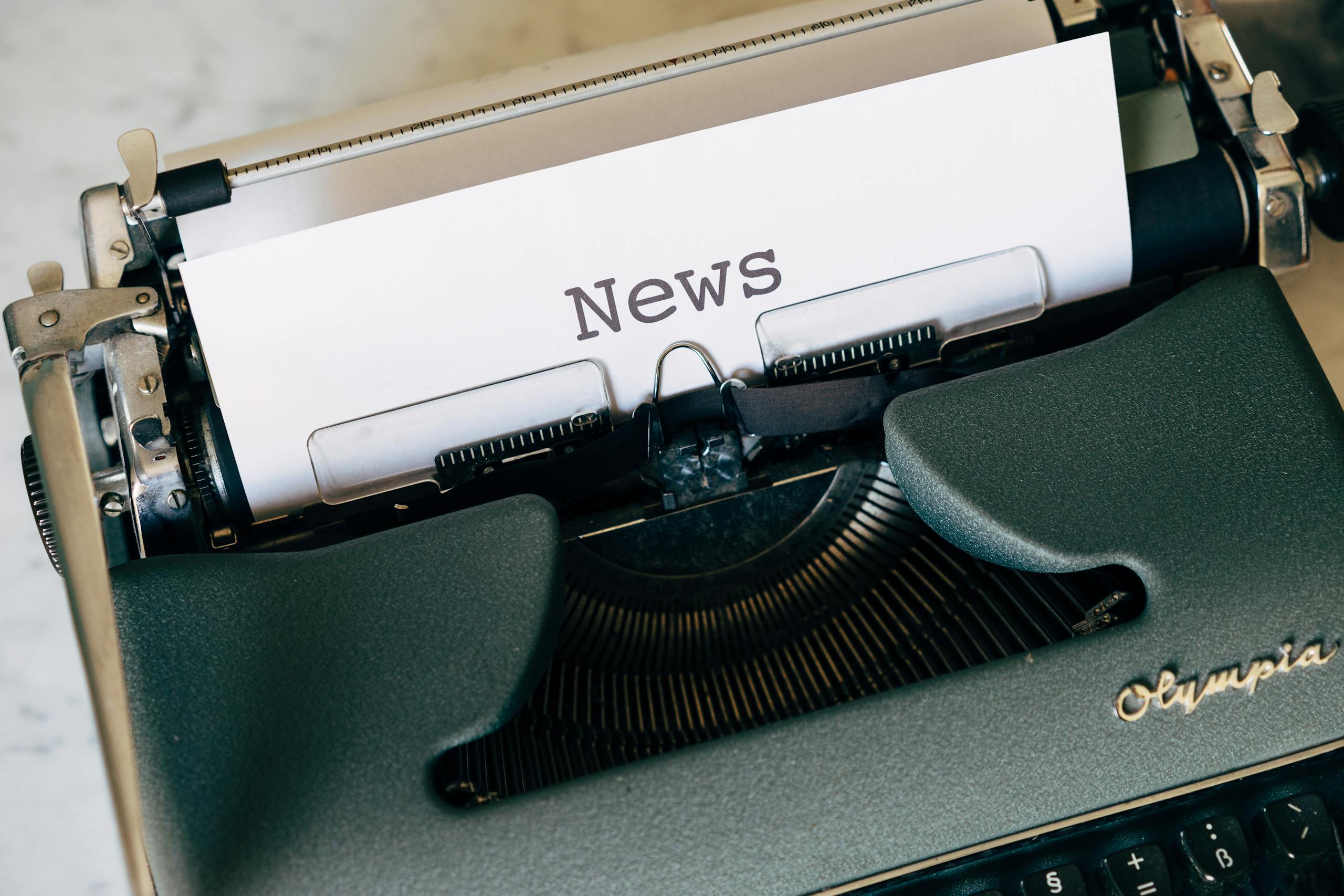 Close-up of a vintage Olympia typewriter with paper reading 'news'. Perfect for classic journalism themes.