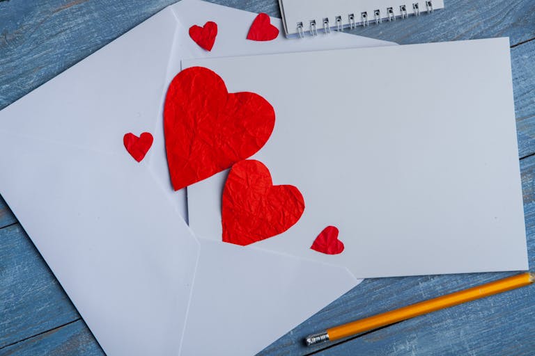 Close-up of red heart cutouts in envelopes on a blue wooden surface, perfect for romantic themes.