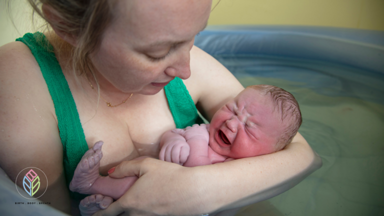 Mother holding newborn baby in a birth pool after a water birth