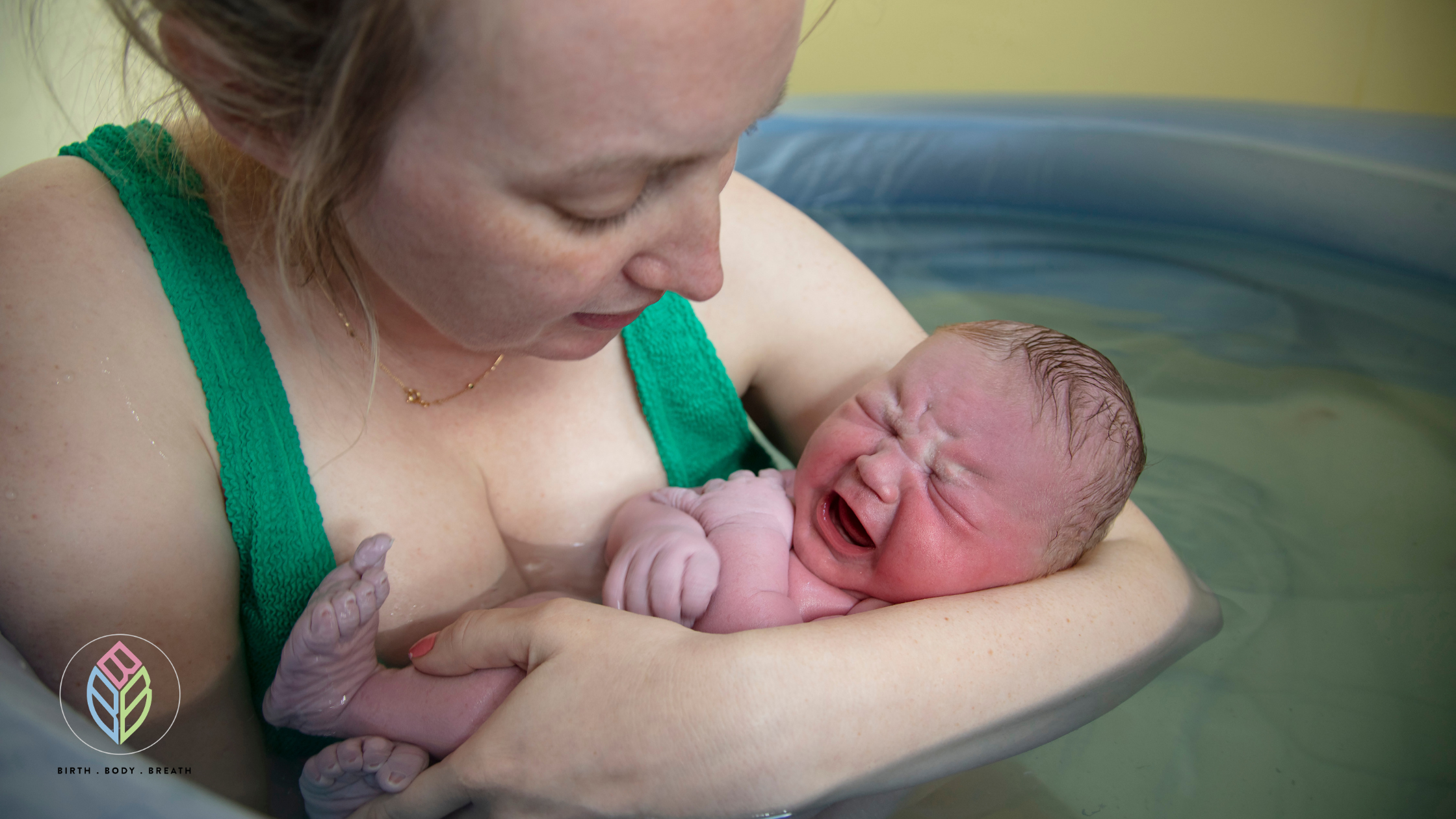 Mother holding newborn baby in a birth pool after a water birth